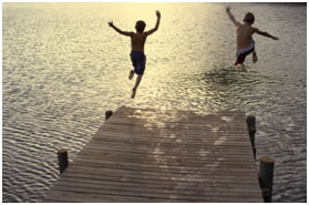 children jumping into lake